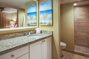 A bathroom with a granite countertop, a sink, a toilet, and a shower area. - Ocean/Pool View 703- Relax and recharge at Fort Myers Beach (Fort Myers Beach)