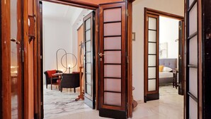 A hotel lobby with a marble floor, a seating area with a sofa and armchairs, and a bed in the background. - 4bnb - Spacious Gracchi Apartment (Rome)