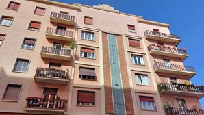 A multi-story residential building with balconies, windows, and a central glass elevator shaft. - 4bnb - Spacious Gracchi Apartment (Rome)
