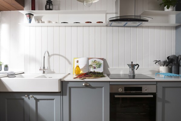 Una cocina moderna con armarios blancos, lavavajillas Bosch y una cafetera.
