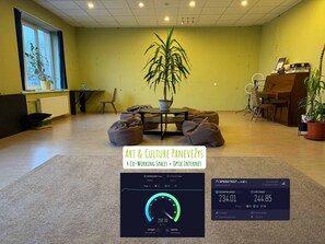A workspace with a large plant, bean bags, a piano, and a computer setup. - Art & Culture Panevėžys, Self Check-In (Panevezys)