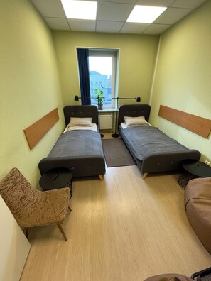 A room with two beds, a desk, a chair, and a view of the outside. - Art & Culture Panevėžys, Self Check-In (Panevezys)