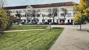 A multi-story building with a flat roof, several windows, and a paved sidewalk in front. - Artihost (Panevezys)