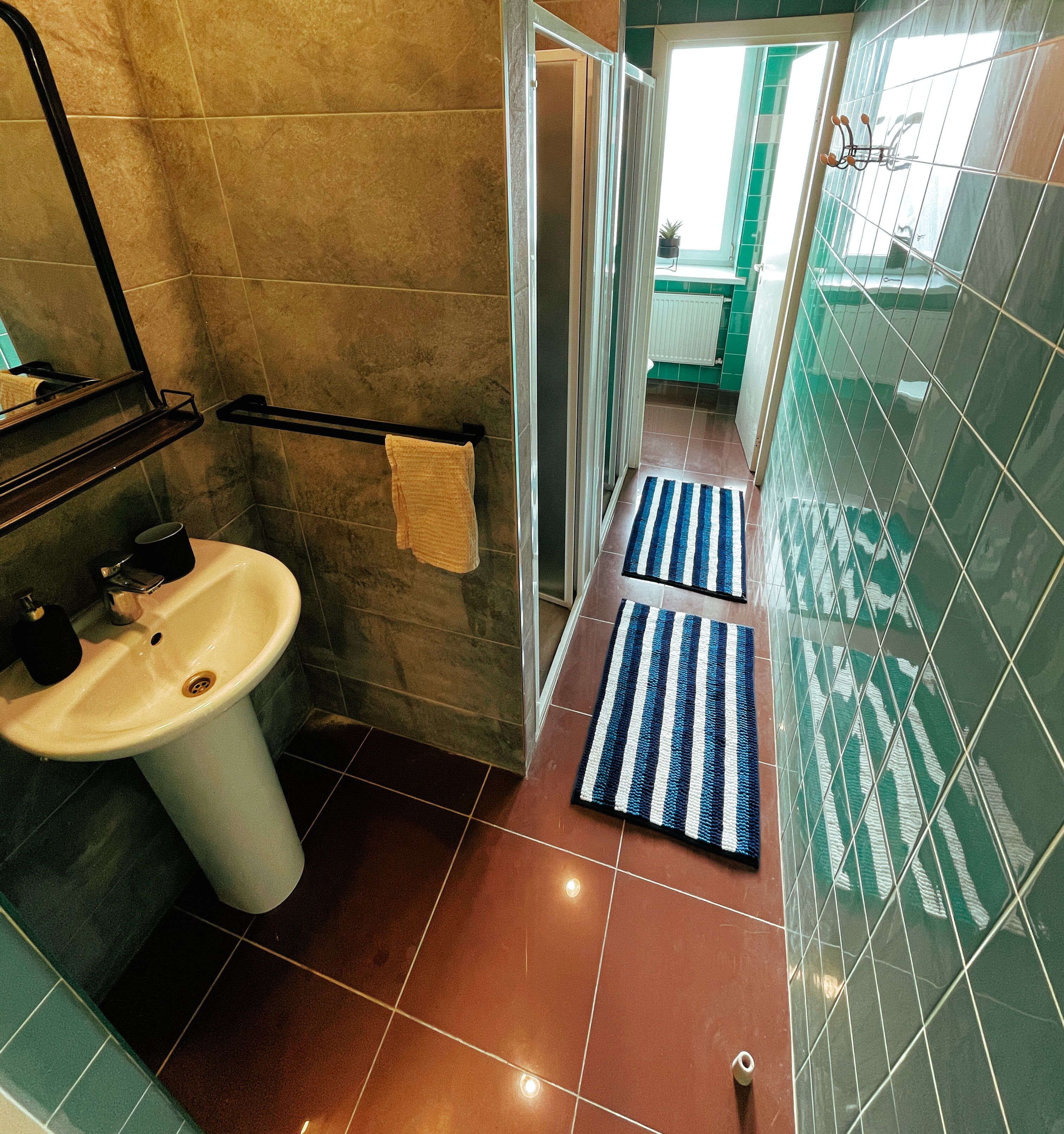 A bathroom with a sink, towel rack, and a shower area.