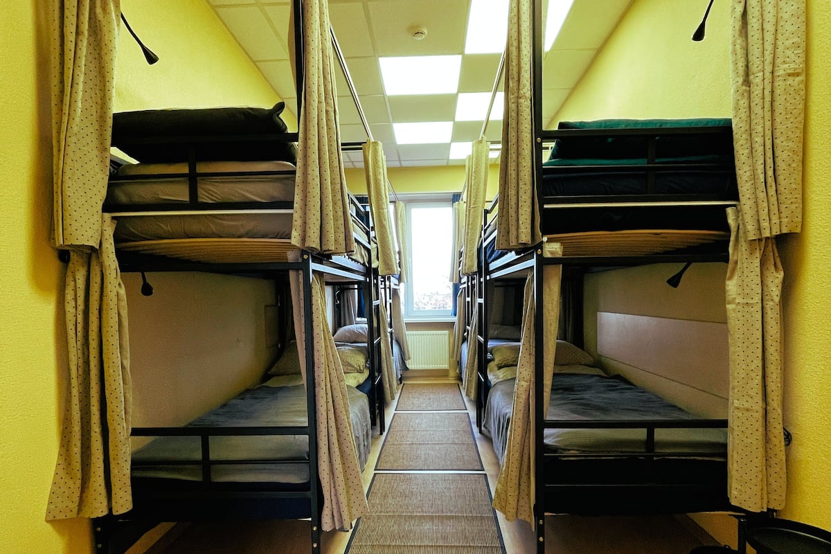 A corridor with bunk beds, a radiator, and a window at the end.