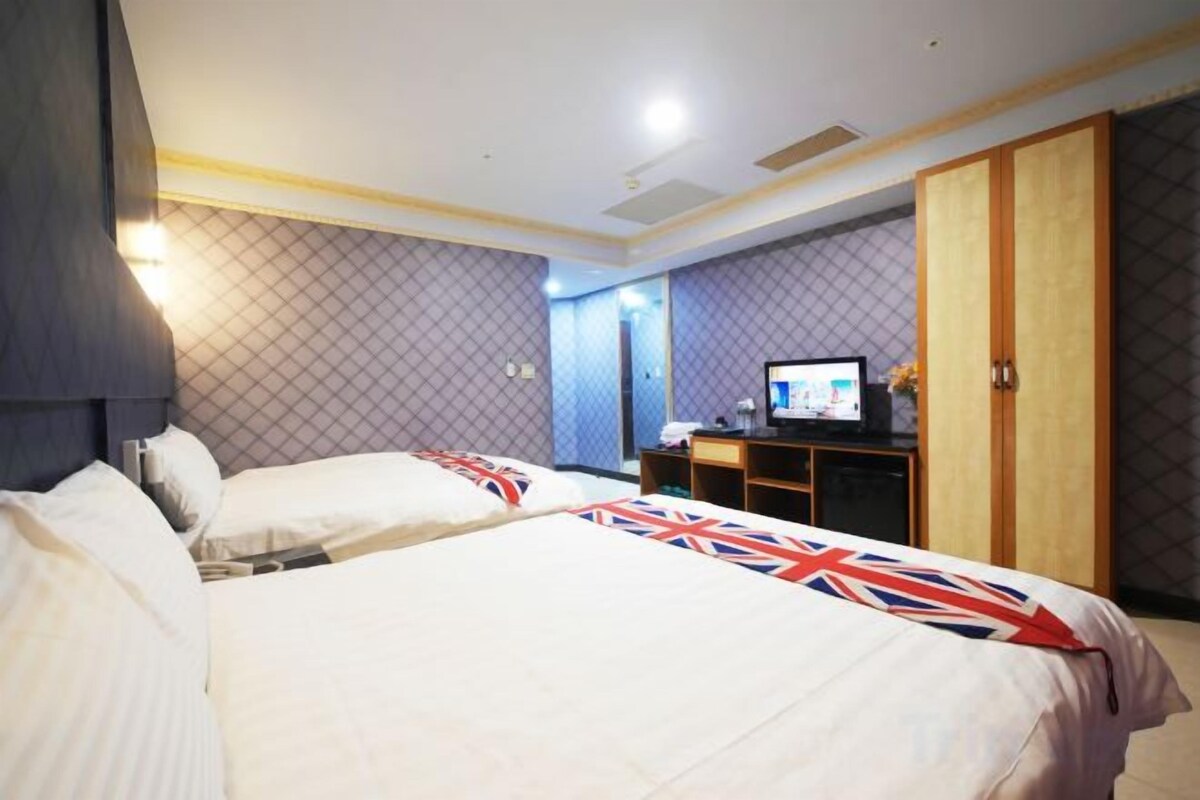 A hotel room with two beds, a desk with a computer, and a wardrobe.