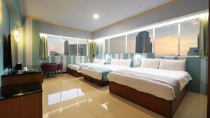 Quarto de hotel com uma cama grande, uma escrivaninha e vista para o horizonte da cidade.