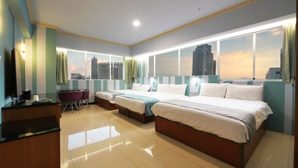 A hotel room with a large bed, a desk, and a view of the city skyline. - IHI loveriver Hotel (Kaohsiung)