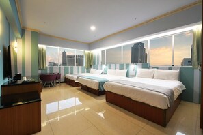 A hotel room with a large bed, a desk, and a view of the city skyline.