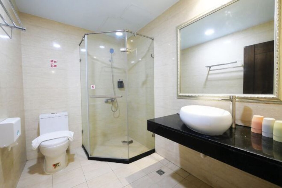Un bagno moderno con doccia vetrata, un water bianco e un piano d'appoggio nero con lavandino bianco e dispenser di sapone.