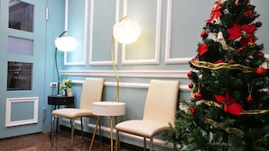 A room with a Christmas tree, two chairs, a small table, and a floor lamp. - IHI loveriver Hotel (Kaohsiung)