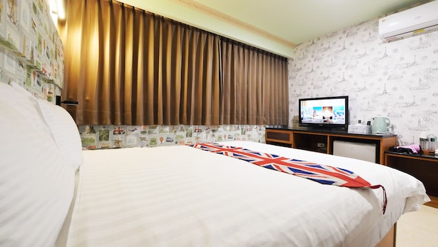 Quarto de hotel com uma cama grande, uma televisão sobre uma mesa e uma cortina.