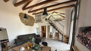 A spacious living area with a wooden dining table set for breakfast, a dark sofa, and a staircase leading to an upper level. - Apartment Olivia (Piran)