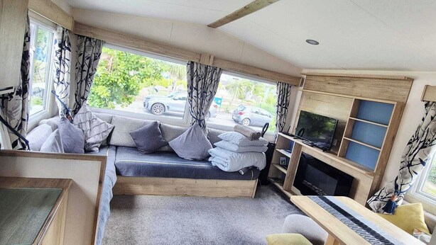 Une pièce confortable avec un canapé-lit, une télévision, une petite table et une fenêtre avec des rideaux.