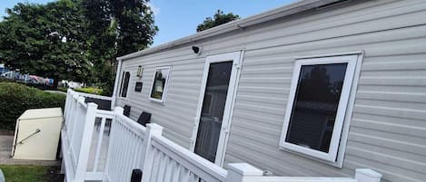 A mobile home with a white exterior, multiple windows, and a white porch railing.