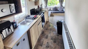 Une petite cuisine équipée avec une cuisinière, un évier et un coin repas comprenant une banquette.