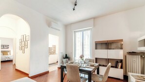 A modern kitchen with a dining area, featuring a large window, white cabinetry, and a central island.