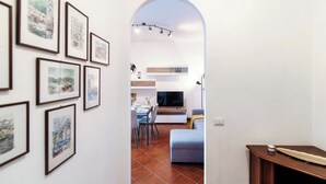 A modern living room with a dining area, a TV, and artwork on the walls.