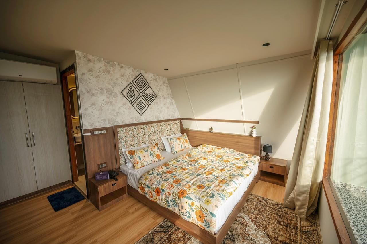 A bedroom with a wooden bed, a nightstand, a wardrobe, and a patterned wall.