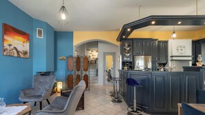 Een moderne keuken met donkere kastjes, een centraal eiland en een eetgedeelte met grijze stoelen.