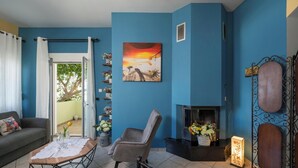 Een woonkamer met een blauwe muur, een open haard, een bank, een stoel en een tafel met een vaas.
