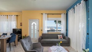 Een woonkamer met een bank, fauteuil, eettafel en een televisie.