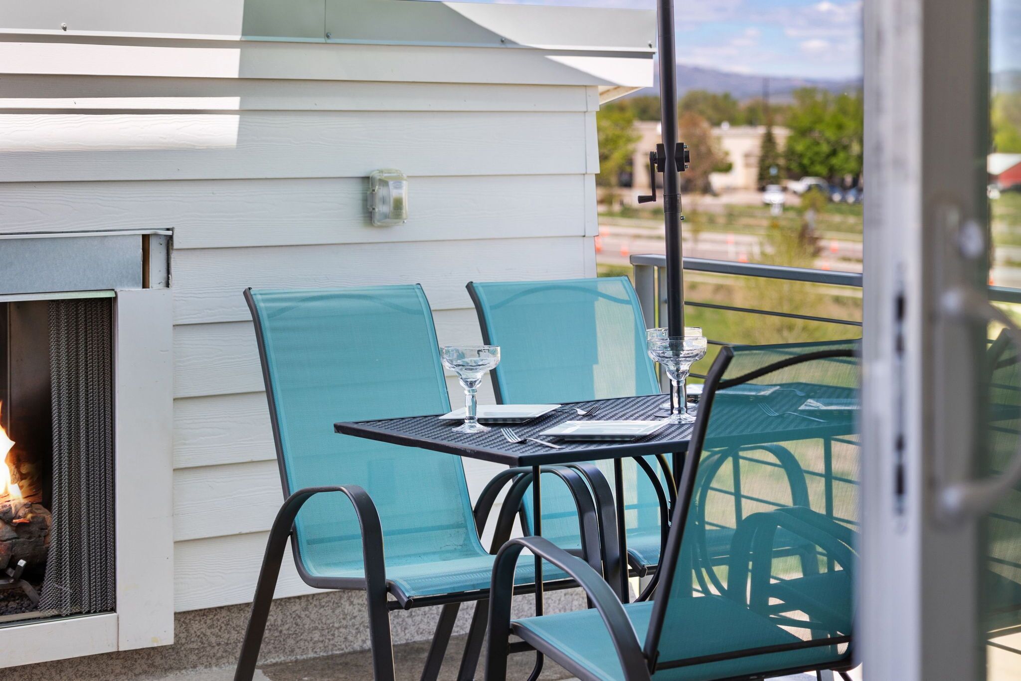 An outdoor patio with a table and chairs, a fire feature, and a view of the surrounding area.