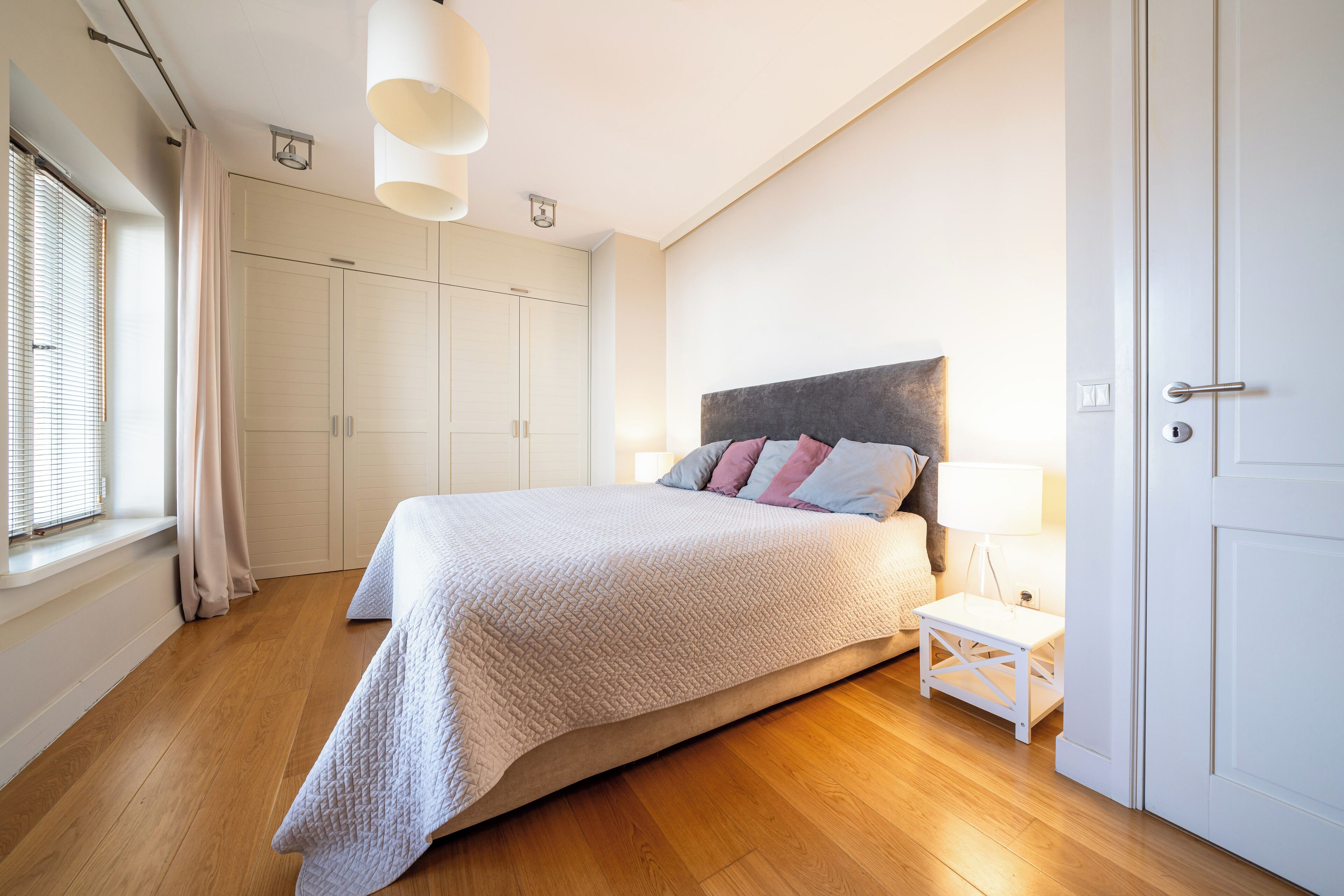 A bedroom with a bed, bedside table, and wardrobe.