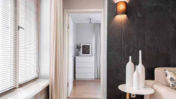 A modern interior with a wooden floor, a white sofa, and a round table with vases. - Charming 1-bedroom apartment with WIFI in Old Tallinn (Tallinn)