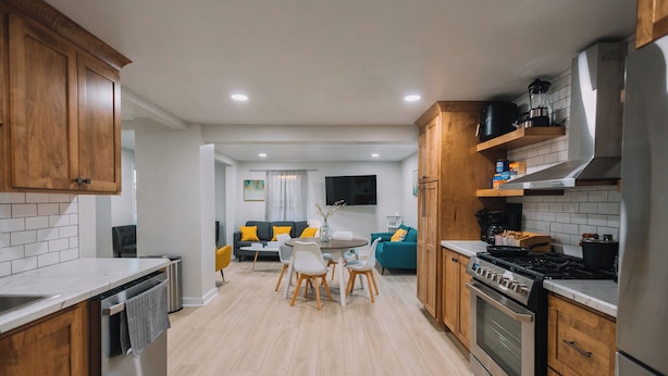 Una cucina moderna con mobili in legno, forno integrato e zona pranzo con tavolo e sedie rotonde.