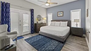 A bedroom with a bed, a ceiling fan, a nightstand, a dresser, and a chair.