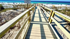 A wooden boardwalk leading to a beach with a sign indicating private beach access.