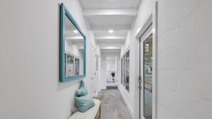 A hallway with a bench, a mirror, and a door leading to an outdoor area. - 237 | Heated Pool | Putting | Outdoor Living | FreeBee Zone | by DelrayNightly (Delray Beach)