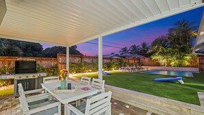 A covered patio area with a grill, pool, and lawn chairs. - 237 | Heated Pool | Putting | Outdoor Living | FreeBee Zone | by DelrayNightly (Delray Beach)