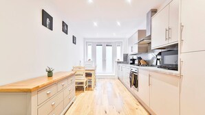 A modern kitchen with wooden flooring, white cabinets, and a dining area with a wooden table and chairs.