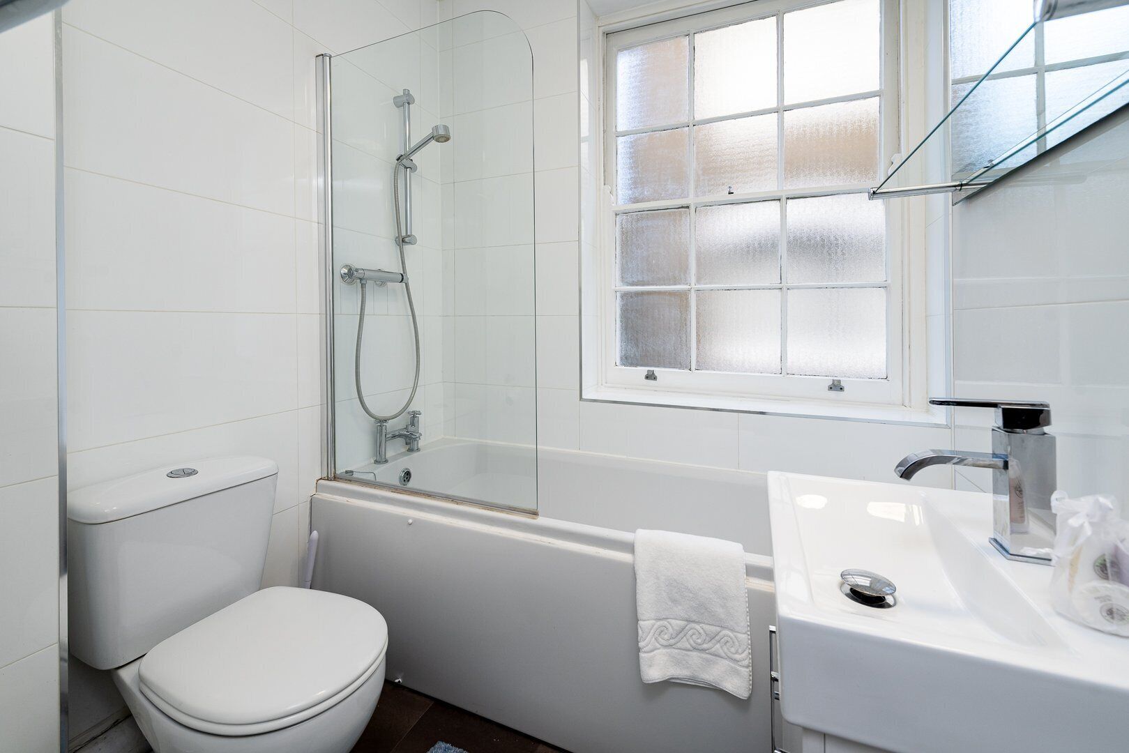 A bathroom with a toilet, a glass-enclosed shower, a bathtub, and a sink with a mirror.