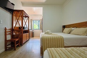 A bedroom with two beds, a wooden desk, and a television.