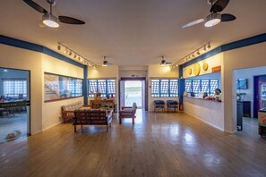 A spacious hotel lobby with a wooden floor, seating area, and a reception desk.