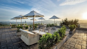 A rooftop terrace with outdoor seating, umbrellas, and potted plants. - W15 Ambuluwawa (Gampola)
