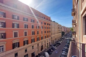 Un immeuble à plusieurs étages, doté de balcons, avec une rangée de voitures garées devant.