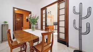 Un comedor con una mesa de madera, sillas, un jarrón con flores y una escultura de cactus.