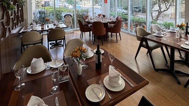 A restaurant with multiple dining tables, chairs, and a large window offering a view of the street.