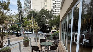 An outdoor patio area with a round table and chairs, surrounded by potted plants and a glass railing.
