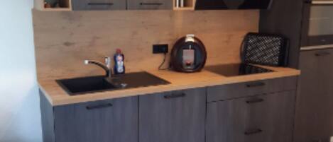 Una cocina moderna con horno empotrado, un fregadero y una máquina de café.