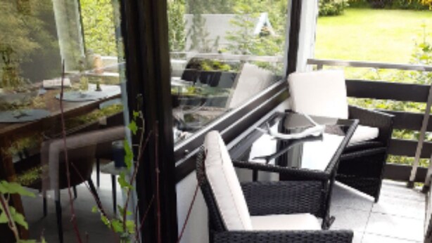 A patio area with a wicker chair, a small table, and a potted plant. - Apartment Wurmbergblick (Braunlage)