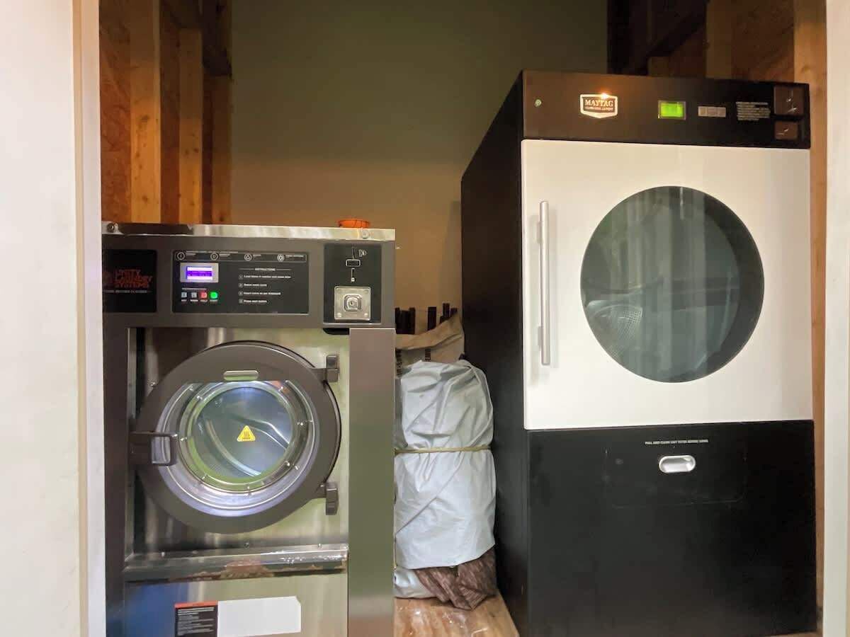 Een kleine wasruimte met een voorlader wasmachine en een gestapelde droger.