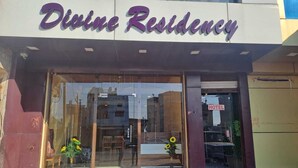 The exterior of Divine Residency with a clear entrance, a 'HOTEL' sign, and a reflection of the surrounding buildings. - Hotel divine and restaurant (Pratapgarh)