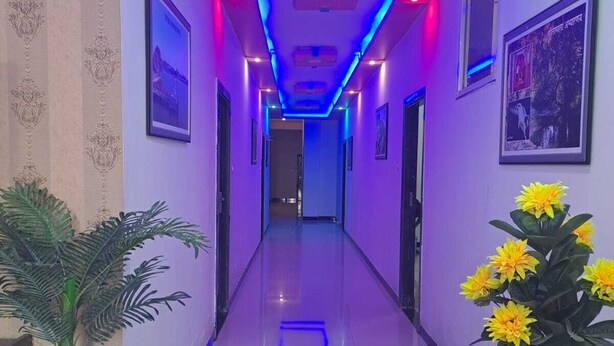 A hallway with a modern design, featuring a reflective floor, decorative lighting, and framed pictures on the walls. - Hotel divine and restaurant (Pratapgarh)