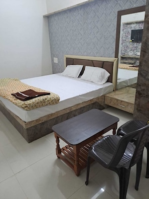 A bedroom with a bed, bedside table, and a chair. - Hotel divine and restaurant (Pratapgarh)