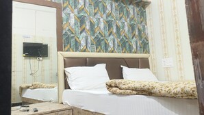 A hotel room with a bed, a bedside table, a mirror, and a patterned wall. - Hotel divine and restaurant (Pratapgarh)